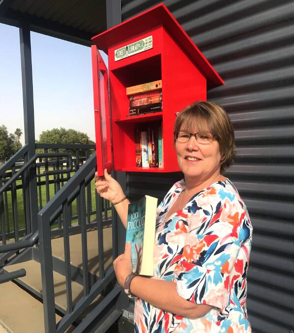 Kathy Prow encourages people to pick up a book, and drop off another, at the new street library in Nelson Park. 