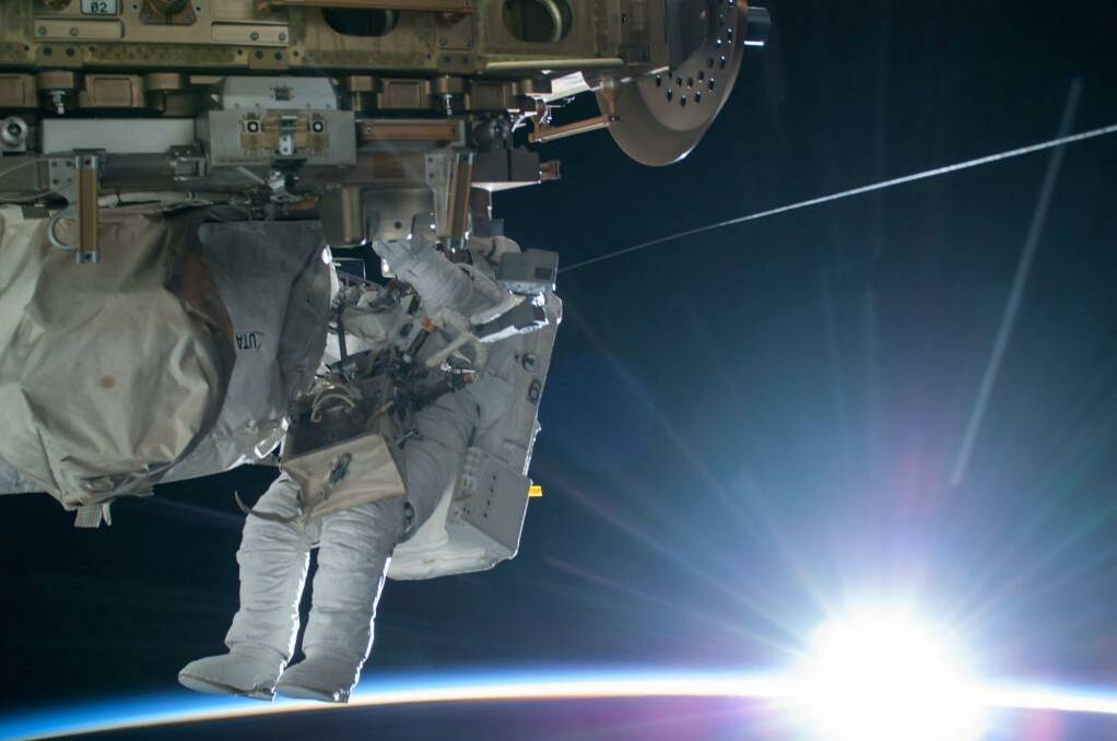 NASA astronaut Terry Virts is seen working to complete a cable routing task while the sun begins to peak over the Earth's horizon on the International Space Station. Photo: NASA