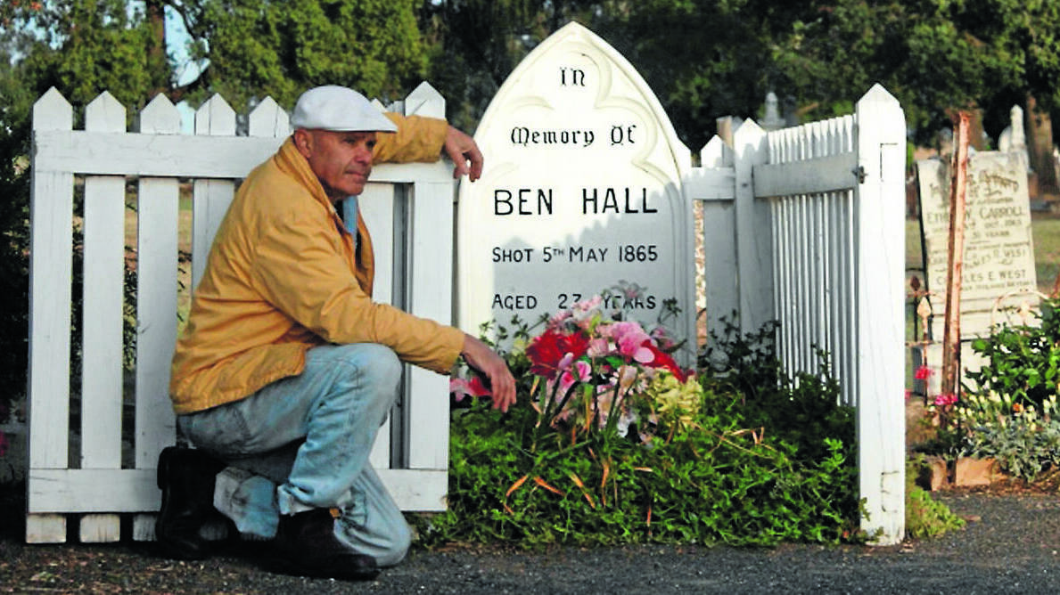 DEAD AND BURIED: Fourth generation descendant of Ben Hall, Peter Bradley, with the well-known grave at Forbes Cemetery.