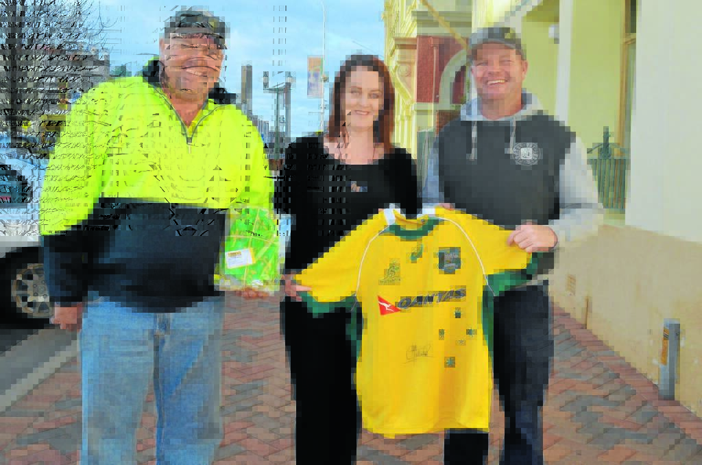 The organising committee for the benefit night including ‘Jack’ Clarke, Tiffany 
Nicholson and Chris Morrison with some of the auction items for the night 
including a signed Wallabies jersey donated by Israel Folau and the first 
item donated, an Enjo kit, from Laurel Hull.
