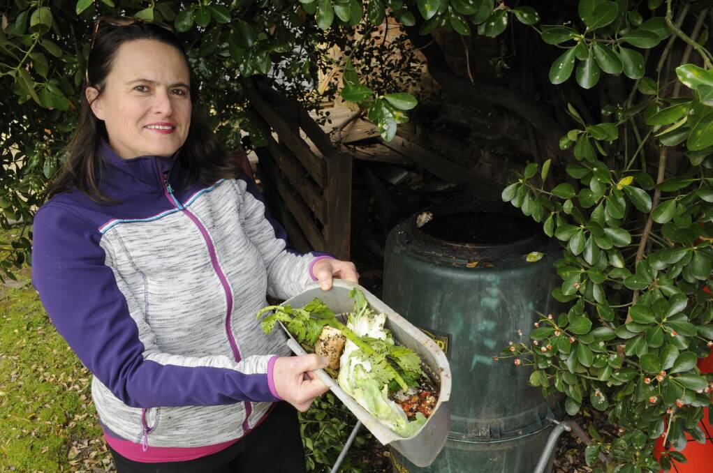 NO FOOD WASTE HERE: Tracey Carpenter takes out some food scraps to the compost bin in her backyard. Photo: CHRIS SEABROOK                                                                                                                                                                                                                      072715cscraps