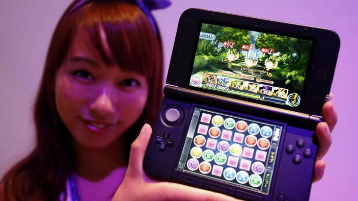 A booth girl holds a Nintendo 3DS displaying GungHo Online Entertainment Inc's new game "Puzzle & Dragons Z" at the Tokyo Game Show on Thursday. Photo: Reuters / Yuya Shino