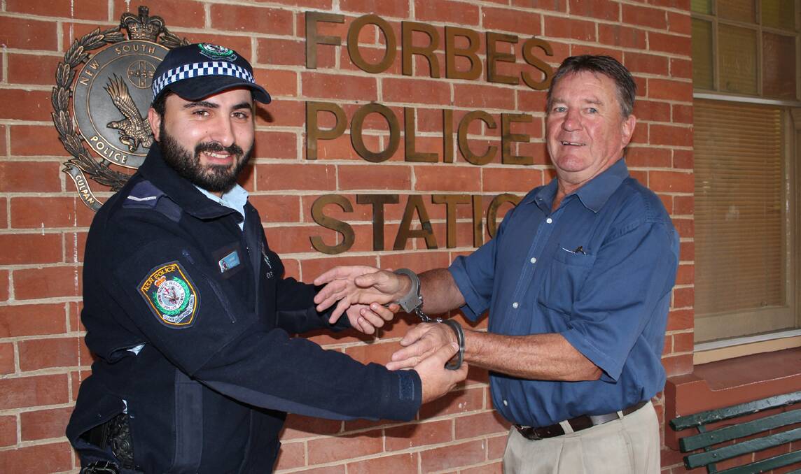 Forbes Police Constable Shunt Yessayan handcuffs Forbes Advocate ­managing editor Barry Shine ahead of the Forbes ‘Fun’ Ball in aid of Forbes Preschool.