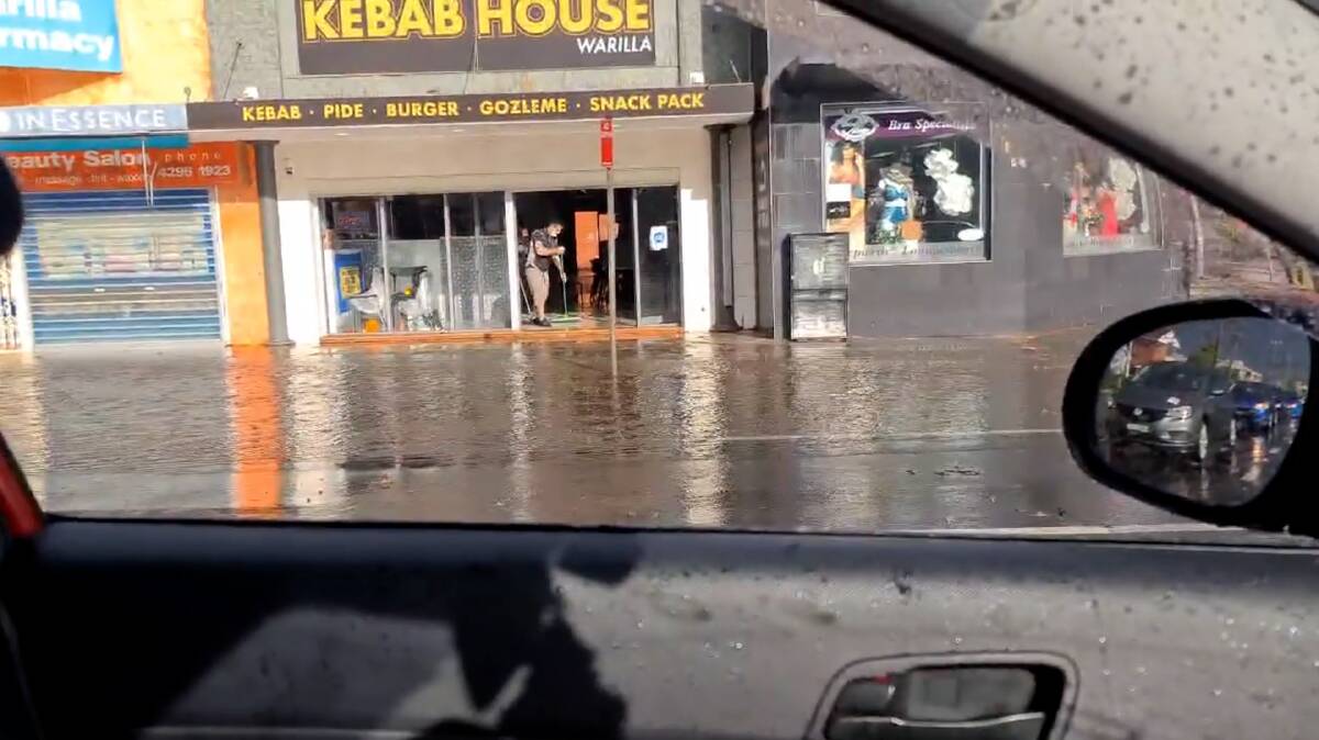 A worker swept water out of Kebab House Warilla after 31mm of rain was dumped on the area on Saturday evening.