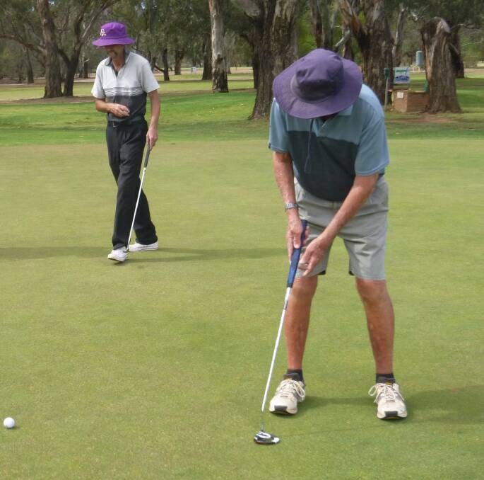 Stroke: Garry Collits putts while George Falvey watches closely.