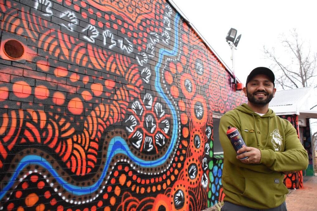 Artist Allan Mckenzie with the vibrant new work on the front wall of Yoorana Gunya Family Healing Centre.