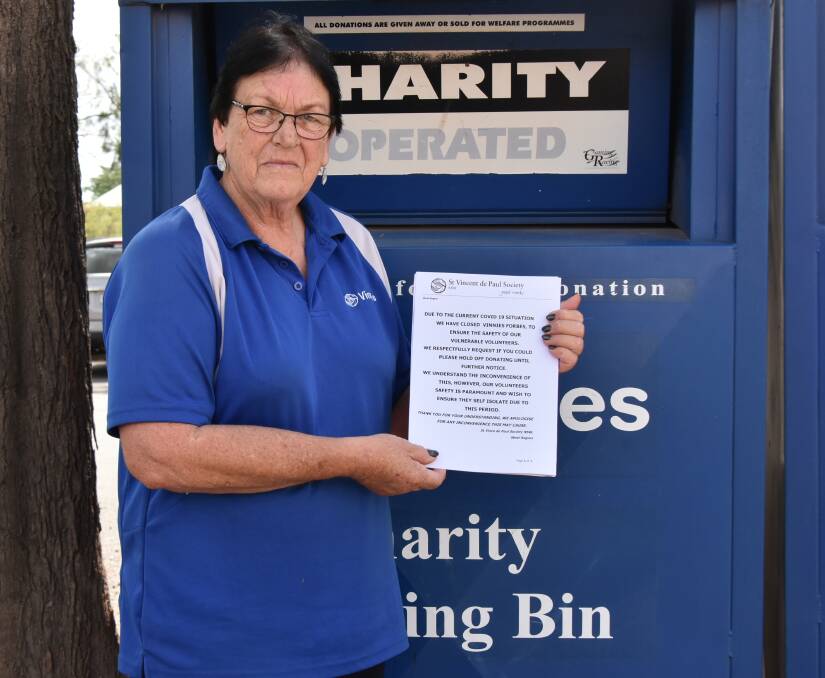 Vinnies volunteer Anne Redfern putting up a sign on the collection bin asking people to hold onto their donations until the local St Vincent de Paul Society shop reopens.