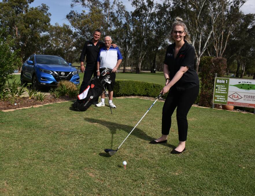 Troy Hurford and Ray Taylor watch on as Hannah Plunkett tees up for the Nissan Golf Classic.