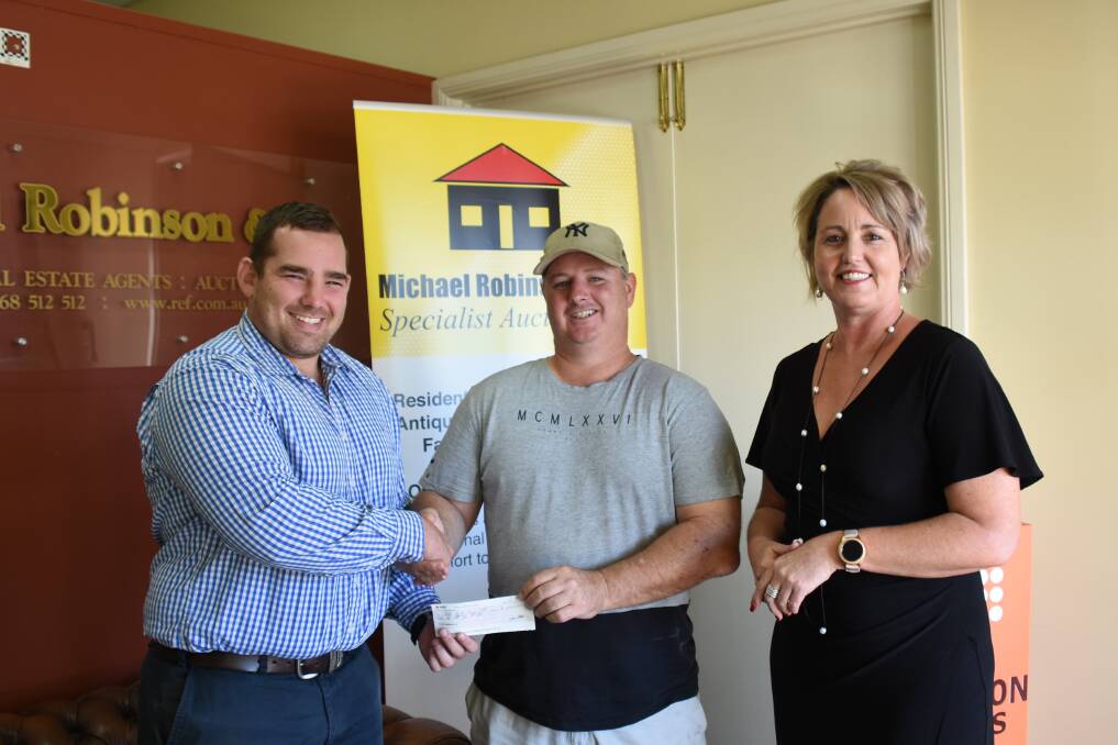 Ben Robinson and Michelle Cheney from Michael Robinson Real Estate present a sponsorship cheque to Magpies President Matthew Coleman.