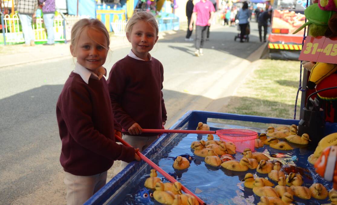 Trying their luck: After a big day competing in the horse events, Isla and Pippa Combe headed to sideshow alley to test their skills. Photo: Bec Bennett.