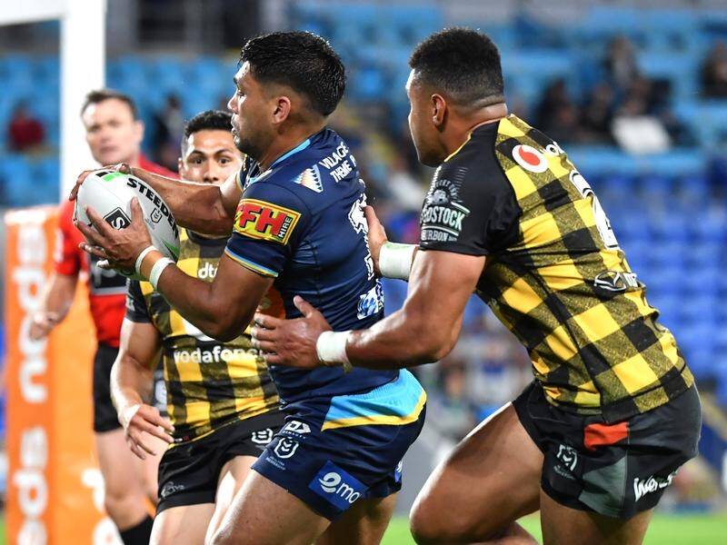 Tyrone Peachey (centre) is grabbed by the Warriors' defence during the Titans' NRL win.