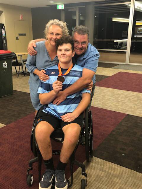 While rugby was a huge part of Jarrod's life before the accident, he found a love for basketball during his recovery. Jarrod and his parents Carolyn and Michael are pictured celebrating his bronze medal at the Kevin Coombs state final.